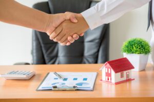 Side view hands of agent and client shaking hands after signed contract buy new apartment.